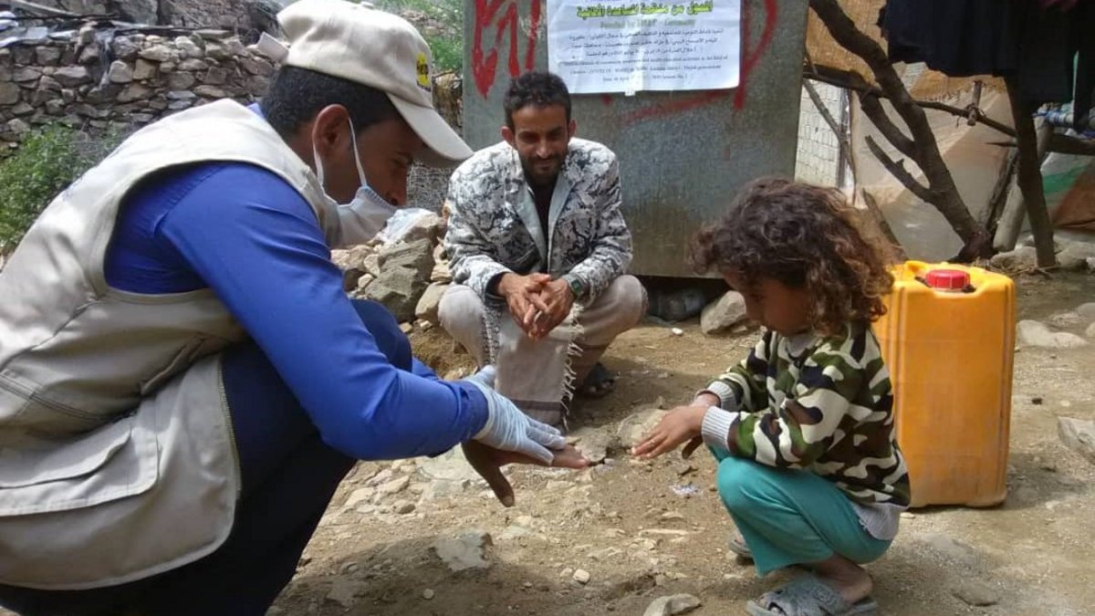 A health worker in Yemen shows a girl how to wash her hands properly