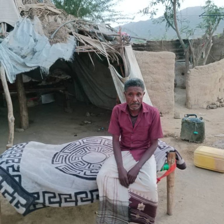 Hassan sits in front of his hut